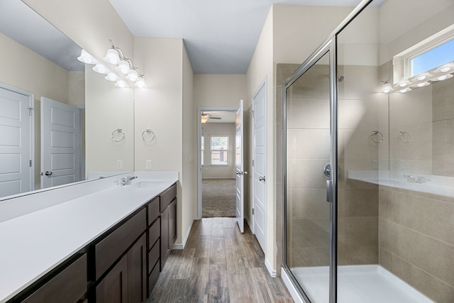 bathroom featuring ceiling fan, wood-type flooring, walk in shower, and vanity