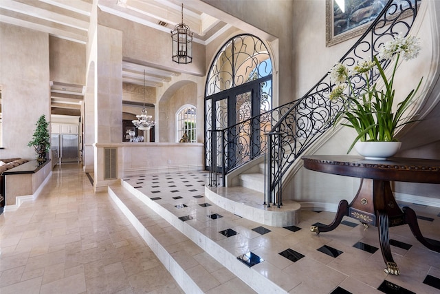 foyer entrance featuring a chandelier, french doors, and a towering ceiling