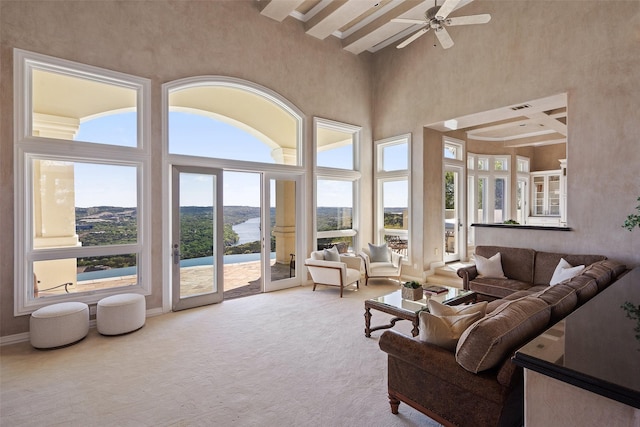 carpeted living room featuring ceiling fan, beamed ceiling, and a towering ceiling