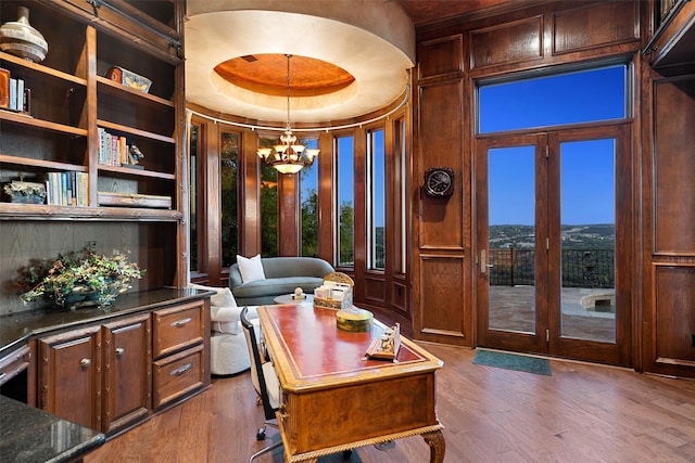 office with a notable chandelier, a raised ceiling, dark wood-type flooring, and french doors