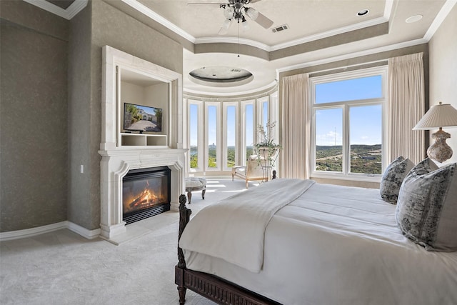 carpeted bedroom featuring ceiling fan, a raised ceiling, ornamental molding, and a fireplace