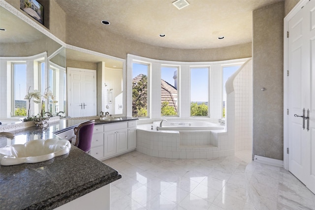 bathroom featuring vanity and tiled bath