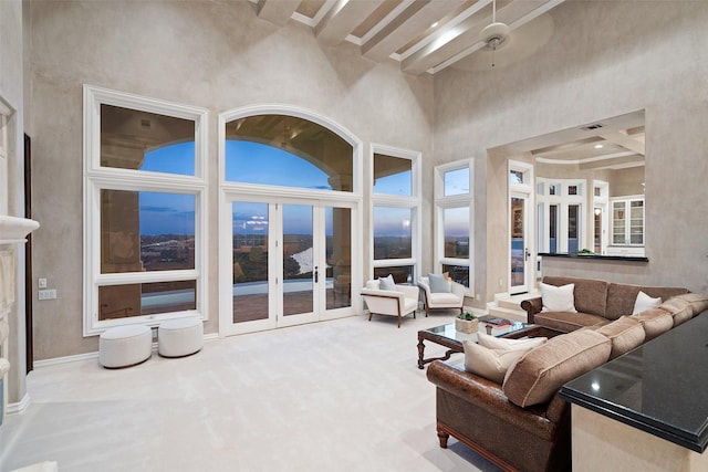 living room with ceiling fan, beam ceiling, a towering ceiling, and french doors