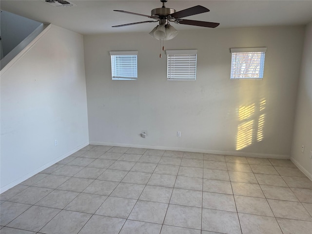 spare room featuring ceiling fan, a healthy amount of sunlight, and light tile patterned floors