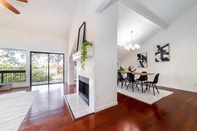 interior space with wood-type flooring, vaulted ceiling with beams, an inviting chandelier, and a tiled fireplace