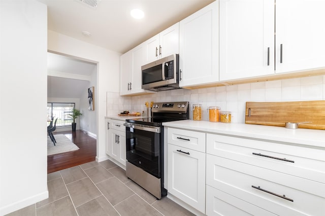 kitchen featuring tasteful backsplash, white cabinetry, light tile patterned floors, and stainless steel appliances