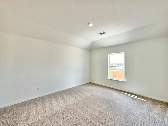 carpeted spare room with vaulted ceiling