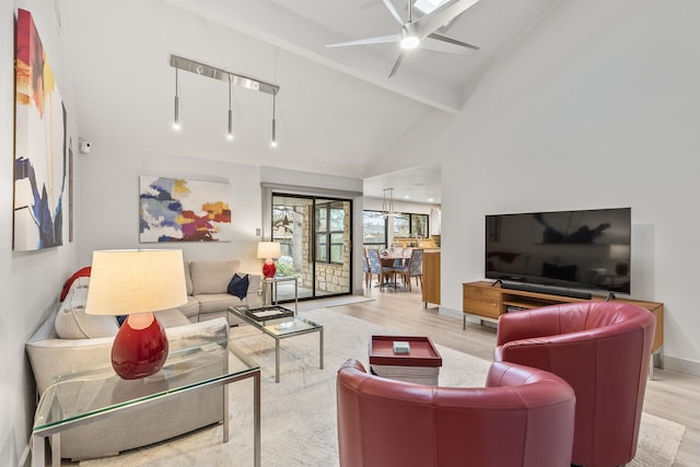 living room with high vaulted ceiling, beam ceiling, ceiling fan with notable chandelier, and light wood-type flooring