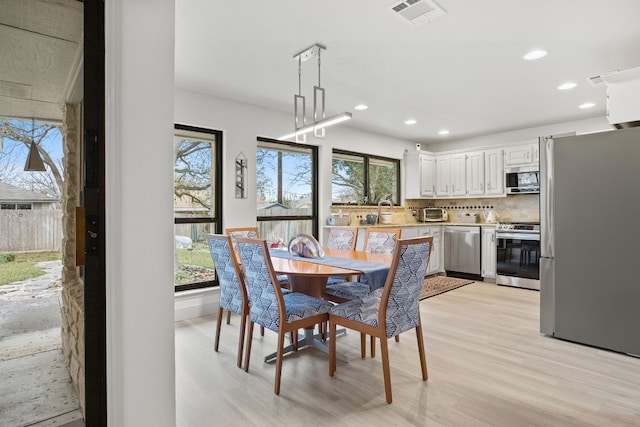 dining space with light wood finished floors, visible vents, and recessed lighting