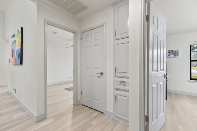 hall featuring baseboards, visible vents, and light wood finished floors