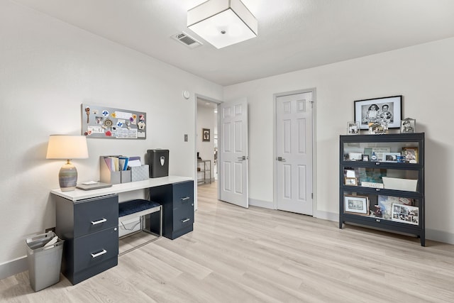 office space with light wood-style flooring, visible vents, and baseboards