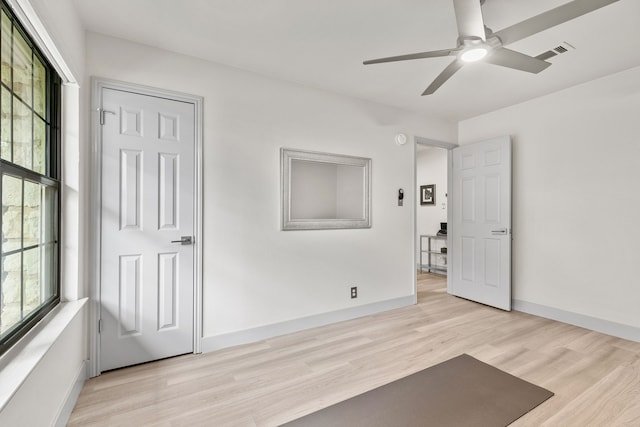 interior space featuring light wood-style flooring, visible vents, ceiling fan, and baseboards