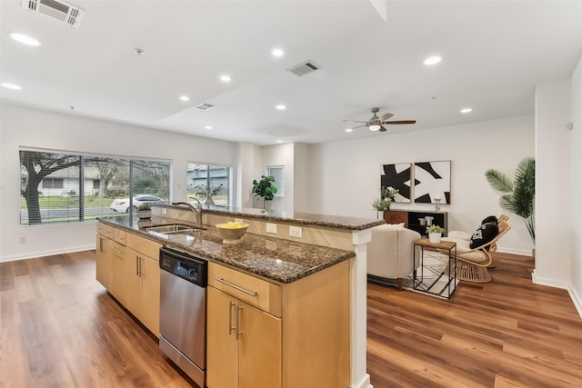 kitchen with dark stone counters, sink, an island with sink, and stainless steel dishwasher