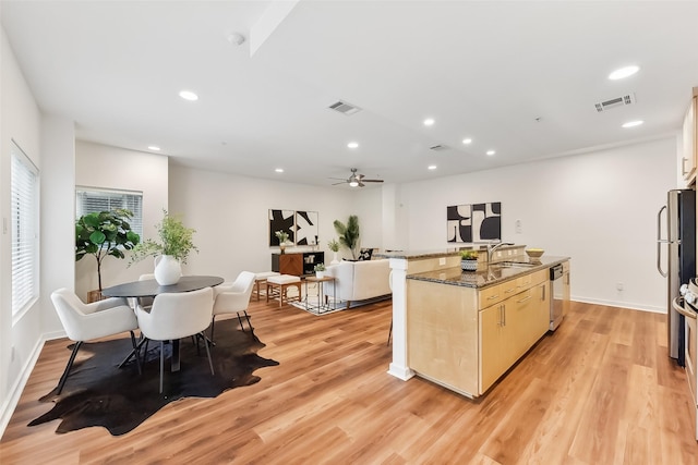 kitchen with ceiling fan, sink, stainless steel appliances, dark stone countertops, and light hardwood / wood-style floors