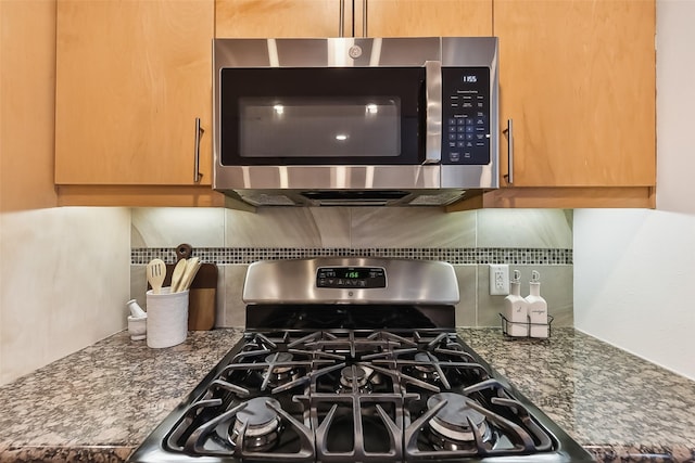 room details featuring backsplash, stainless steel appliances, and dark stone counters