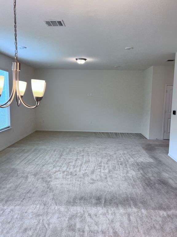 carpeted empty room with a chandelier