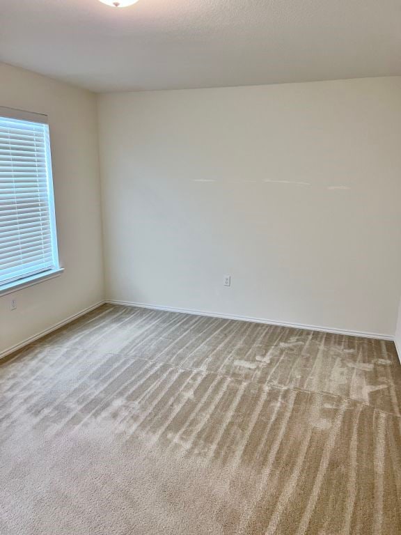 spare room featuring light carpet, plenty of natural light, and a textured ceiling