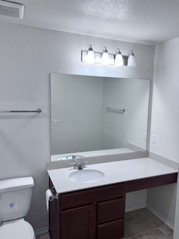 bathroom featuring tile patterned floors, vanity, toilet, and a textured ceiling