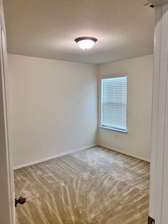 carpeted spare room with a textured ceiling