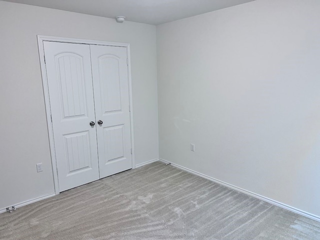 unfurnished bedroom featuring light carpet and a closet