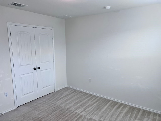 unfurnished bedroom with light colored carpet and a closet