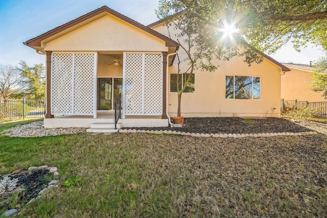 back of house with ceiling fan and a lawn