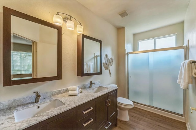 518 Texas Dr, Georgetown, TX 78633 - bathroom with wood finished floors, a stall shower, double vanity, and toilet