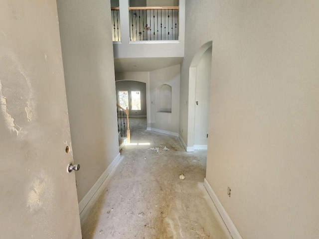 corridor with a towering ceiling, baseboards, and arched walkways