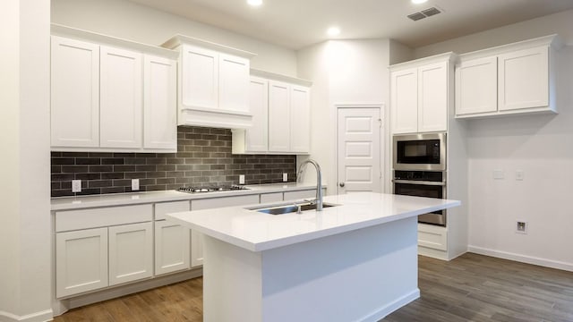 kitchen with stainless steel appliances, a sink, white cabinetry, visible vents, and decorative backsplash