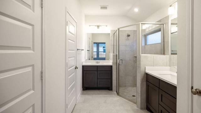 bathroom featuring a stall shower, two vanities, and visible vents