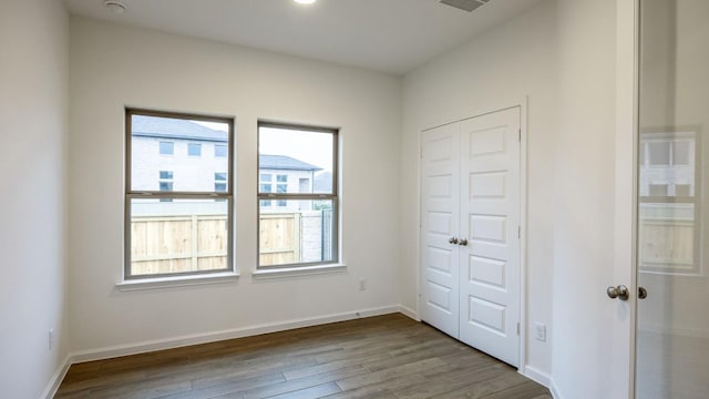 unfurnished bedroom featuring a closet, baseboards, and wood finished floors