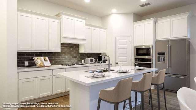 kitchen with visible vents, white cabinets, decorative backsplash, appliances with stainless steel finishes, and light countertops