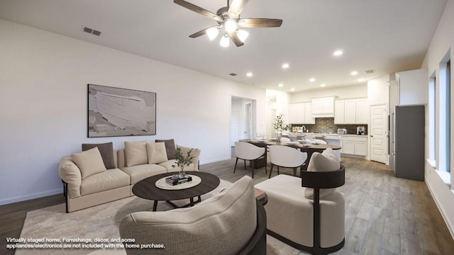 living area featuring light wood-type flooring, baseboards, and visible vents