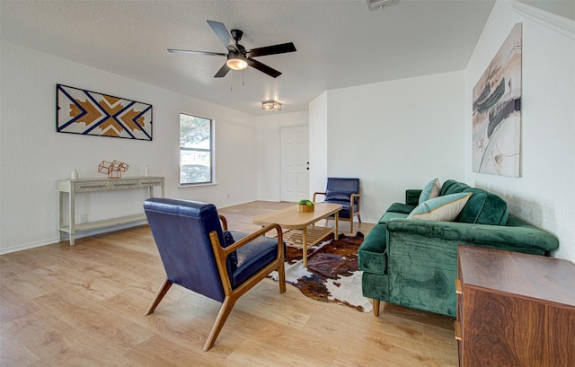 living room with a textured ceiling, light hardwood / wood-style flooring, and ceiling fan