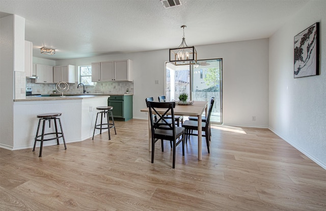 dining room with light hardwood / wood-style floors, an inviting chandelier, plenty of natural light, and sink