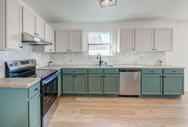 kitchen featuring sink, green cabinetry, light hardwood / wood-style floors, white cabinetry, and stainless steel appliances