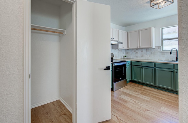 kitchen with white cabinetry, electric range, sink, tasteful backsplash, and light hardwood / wood-style flooring