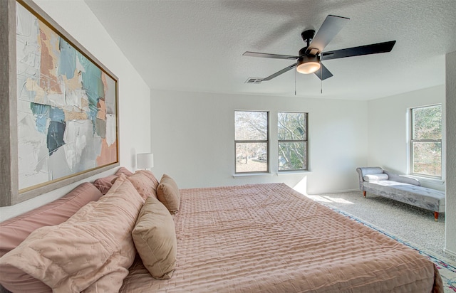 carpeted bedroom featuring ceiling fan and a textured ceiling