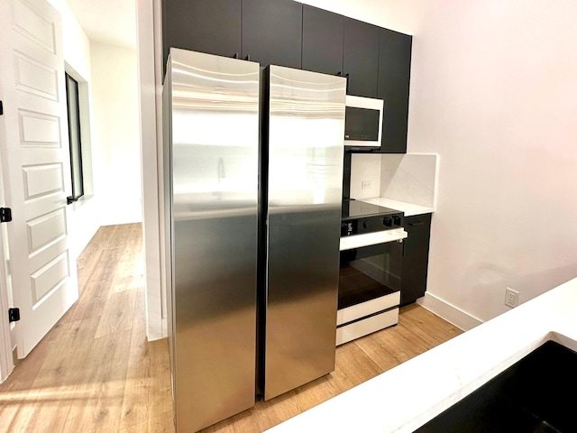 kitchen with stainless steel refrigerator, light hardwood / wood-style flooring, and range