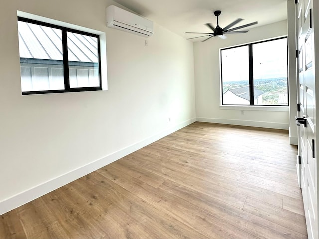 unfurnished room with ceiling fan, a wall unit AC, and light hardwood / wood-style flooring