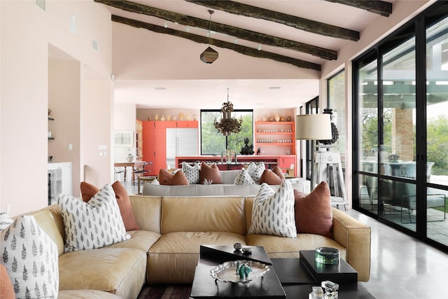 living room with vaulted ceiling with beams, concrete flooring, and a notable chandelier