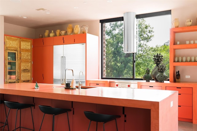 kitchen featuring a breakfast bar area, built in refrigerator, and sink