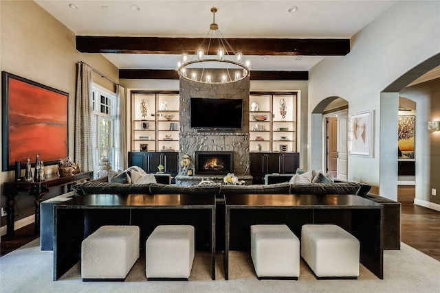 living room featuring a fireplace, built in features, beamed ceiling, and an inviting chandelier