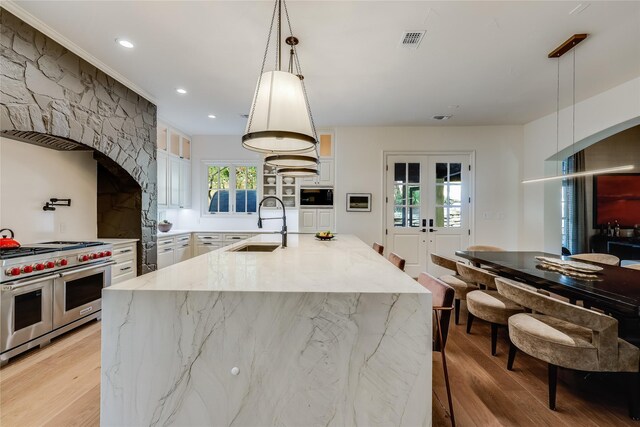 kitchen featuring pendant lighting, range with two ovens, french doors, and sink