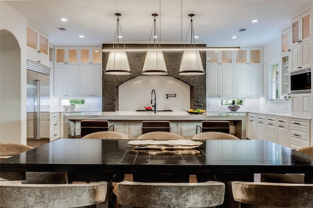 kitchen featuring a kitchen bar, stainless steel built in fridge, a spacious island, and sink