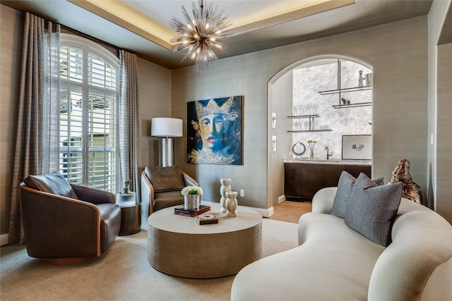 living room with a notable chandelier and a tray ceiling