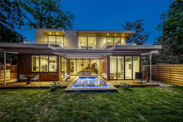 rear view of property featuring a yard, a balcony, and a pool side deck