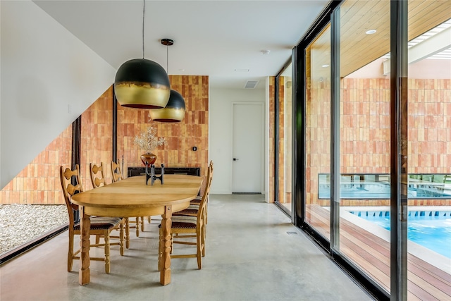 dining space featuring floor to ceiling windows and concrete floors