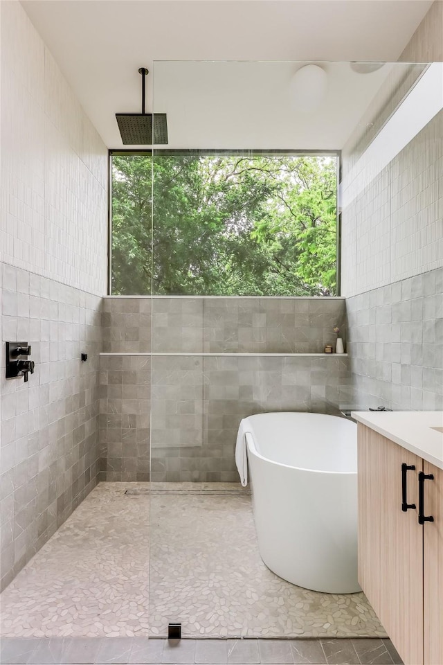 bathroom with tile patterned floors, a wealth of natural light, separate shower and tub, and tile walls