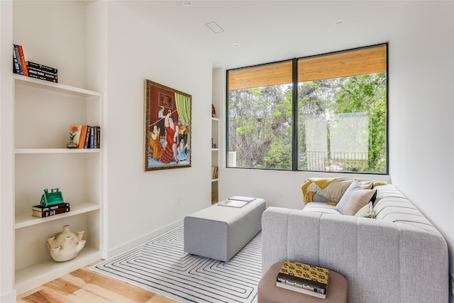 living room featuring built in shelves and hardwood / wood-style flooring